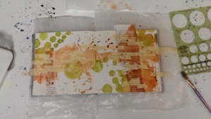 Step four:  The addition of some serpentine green while the orange is still wet, using a circle template to push the paint through to the page.